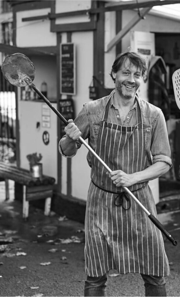 Michael Law preparing pizza in his wood-fired oven